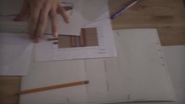 Adam eli dikkatle çalışıyor. Küçük bir iş projesine odaklanmış. Ahşap masa üzerinde çalışıyor.