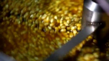 Otomatik patlamış mısır makinesinde karamel aromalı tatlı soslu peynirle karıştırılmış küçük mısır tohumlarını yakından çek.