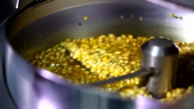 Otomatik patlamış mısır makinesinde peynir, karamel aromalı tatlı sosla karıştırılmış küçük mısır tohumlarını yakından çek.