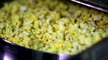 Otomatik patlamış mısır yapma makinesinin kapağı açılıyor. Karamelli tatlı peynir mısır tohumları yakın planda patlıyor.