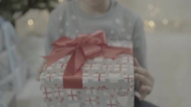 Mutlu çocuğun Noel hediyesi kutusunu açmasına yakından bakın. Yeni yıl ağacının yanında otururken şaşkınlık içinde.