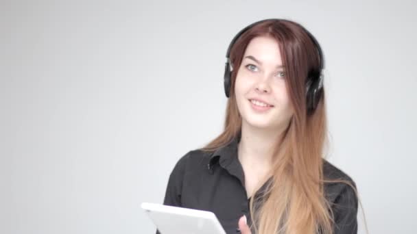 Mujer Joven Guapa Auriculares Con Tableta Blanca Sonríe Fondo Claro — Vídeos de Stock