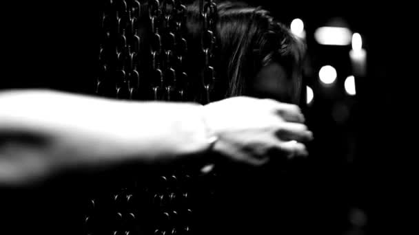 チェーンカーテンの後ろに立つ美しい若い女性の近くの黒い白い暗い背景神秘的なビューの手の動き — ストック動画
