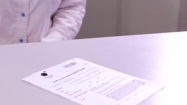 Kadın veznedarın beyaz arka planda a4 sayfa kağıt başvuru formu ve plastik kartı takas ederken yakın plan çekimleri.