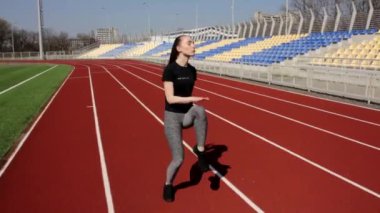 Çekici genç fit aktif bayan sporcu kaslarını ısıtıyor güneşli bir günde büyük stadyumun dışında egzersiz yapıyor.