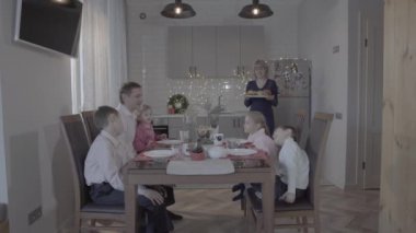 Mutlu dört çocuk, yeni yılı kutluyor. Mutfak masası, baba, oğul, anne, yemek servisi yapıyor.