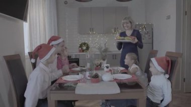 Mutlu, heyecanlı altı kişilik aile Noel yemeğinin tadını çıkarın. Güzel, rahat bir mutfak kutlaması atmosferinde, Noel Baba şapkalarıyla.