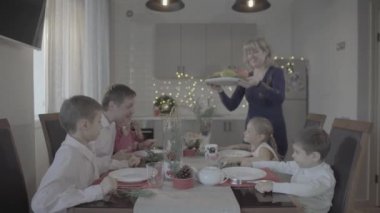 Mutlu, heyecanlı altı kişilik bir aile, neşeli atmosferli, rahat bir mutfakta güzel bir Noel yemeği kutluyor.