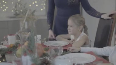 Sevgi dolu anne, yemek masasında oturan tatlı kızı öpüyor Noel 'i sıcacık bir festival atmosferinde kutluyor.