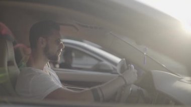 Çekici, yakışıklı, güneş gözlüklü genç adam lüks spor yarış arabasında oturuyor rakibinin karşısında başlamaya hazır.