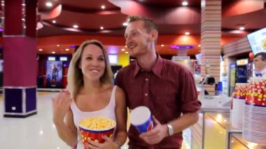 Genç, mutlu, güzel, heyecanlı kadın çift patlamış mısır yiyor, gazoz içiyor sinemalara doğru yürüyor.