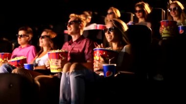 Bir grup heyecanlı, mutlu, çekici erkek arkadaş patlamış mısır yiyor. 3D aksiyon sinemasının tadını çıkarıyorlar.