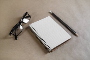 Kağıt arka plan boş defter, gözlük ve zanaat üzerinde kalem.