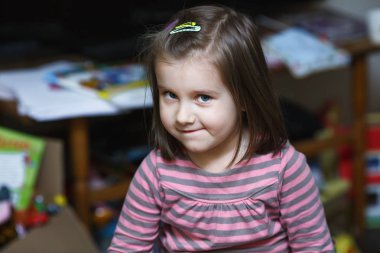 Kız çocuk gülümseyen portresi. Çocuk kameraya doğru görünüyor.