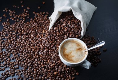 Kahve fincanı, kahve çekirdekleri ve tuval çanta fotoğrafı.