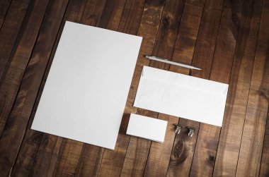 Ahşap masa arkaplanındaki boş kırtasiye seti fotoğrafı. Şirket kimlik şablonu. Tepkili tasarım modeli.