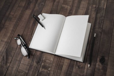 Boş açık kitap ve Kırtasiye ahşap masa arka plan üzerinde. Duyarlı tasarım mockup.