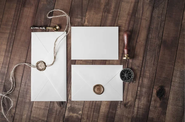Blank paper envelopes with wax seal, stamp and stationery on vintage wood background. Flat lay.