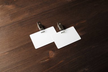 İki boş plastik rozetleri mockup ahşap arka plan üzerinde. Boş ad etiketi kadar sahte. Metin için yer.