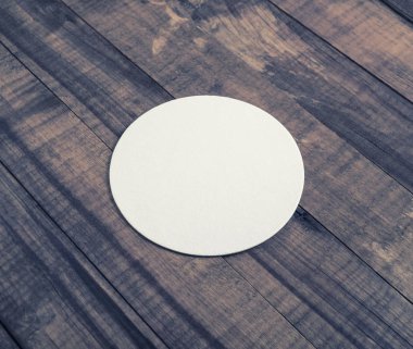 Ahşap arka plan boş beyaz bira altlığı.