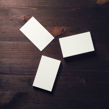 Üç koyu ahşap arka plan üzerinde beyaz iş kartları boş. Mockup kimlik marka için. Düz yatıyordu.
