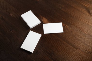 Üç ahşap masa arka plan üzerinde beyaz iş kartları boş. Mockup kimlik marka için.
