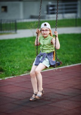 Salıncak ciddi kız. Çocuk Bahçesi. Seçici odak.