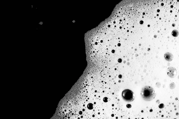 Soap sud. Foam with bubbles on black background. Detergent in water. Flat lay.