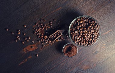 Kavrulmuş kahve çekirdekleri ve ahşap mutfak masasında öğütülmüş toz. Düz yatıyordu.