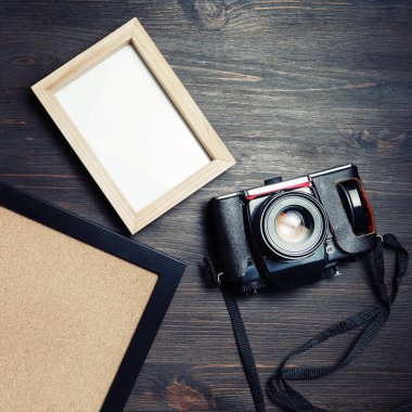 Ahşap masa arkasında eski kamera ve boş fotoğraf çerçeveleri. Düz yatıyordu.