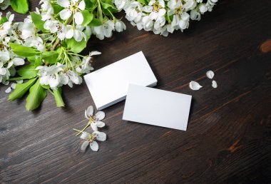 Boş beyaz kartvizitlerin ve ahşap masa arkasındaki çiçeklerin fotoğrafı. Metin için alanı kopyala.