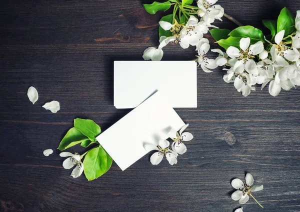 Blank business cards and and flowers on wood table background. Template for branding ID. Top view. Flat lay.