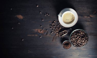 Eski bir kahve fonu. Kahve fincanı, kahve çekirdekleri ve ahşap mutfak masasında öğütülmüş toz. Metnin için alanı kopyala. Düz yatıyordu.