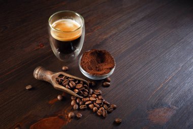 Kahve fincanı, kavrulmuş kahve çekirdekleri ve ahşap arka planda öğütülmüş toz ile hayat. Metnin için boşluk kopyala.