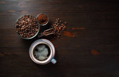 Eski kahve arkaplanı ve mesaj için yeri var. Kahve fincanları, kahve çekirdekleri ve ahşap masa zemininde öğütülmüş tozla dolu bir hayat. Düz yatıyordu.