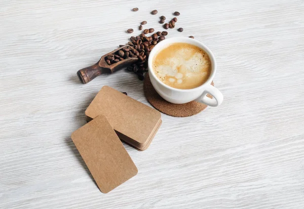 Blanco Kraftpapier Visitekaartjes Koffiebeker Gebrande Koffiebonen Een Lichte Houten Ondergrond — Stockfoto