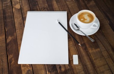 Kırtasiye ve kahve. Defter, kahve fincanı, tahta masa arkasındaki silgi ve kalem. Metnin için boşluk kopyala.