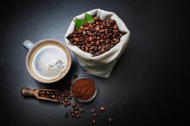 Kahve fincanı, kavrulmuş kahve çekirdekleri ve arka planda siyah mutfak masası tozları. Nefis taze kahve..