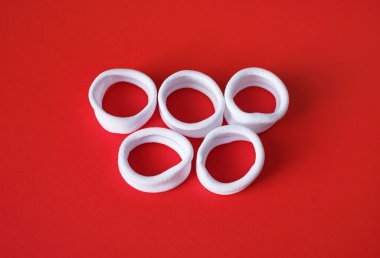 Kırmızı zemin üzerinde olimpiyat halkaları şeklinde beyaz kumaş bilezikler..