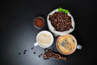 Taze kahve. Kahve fincanları, kahve çekirdekleri ve siyah masa arkasında öğütülmüş toz. Düz yatıyordu.