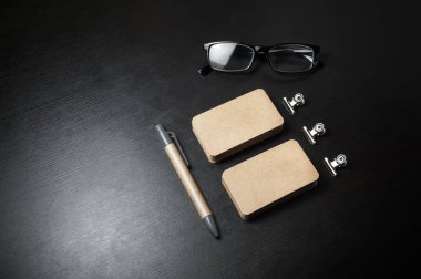 Siyah ahşap arka planda boş Kraft kırtasiye seti. Kartvizit, kalem ve gözlük. Damgalama kimliği şablonu.