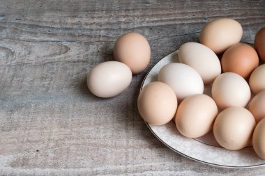 Sağdaki ahşap masada beyaz bir tabak var. Tavuklu yumurtalar bayram için pişirmek ve boyamak için.