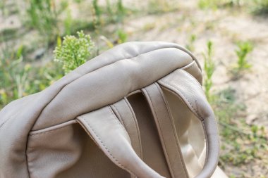 Kahverengi bir sırt çantasının arka kısmının arka plandaki çimlere göre görüntüsü