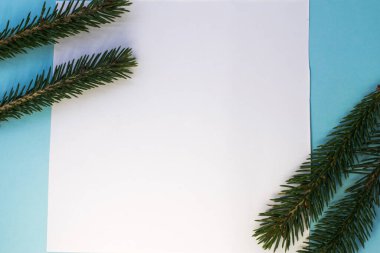 Ortadaki mavi arkaplanda ladin dallarının üst köşelerinin yer aldığı beyaz bir kağıt var. Yeni yıl arkaplanını karşılamak için düzenName