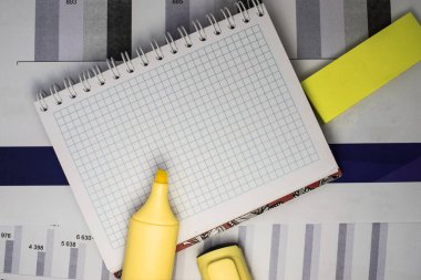 İçinde boş bir kağıt ve ofis malzemesi olan açık bir not defteri şemayı gösteren finansal belgelerde yer almaktadır.