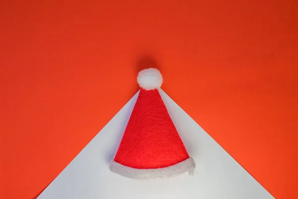 White triangle on a red background. On the triangle is a Santa Claus hat. The view from the top