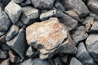 Sahildeki kayalar. Küçük taşların arasında büyük kırmızı karınlı bir taş yatar. Güzel arkaplan duvar kağıdı ekran koruyucusu