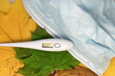 Sonbaharda akçaağaç ardında tıbbi bir maske ve elektronik termometre bırakır. Önleme ve sağlığınıza dikkat etme kavramı