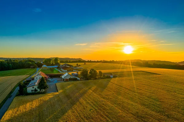 Coucher de soleil lumineux vue aérienne dans une ferme avec un immense champ au premier plan. — Photo