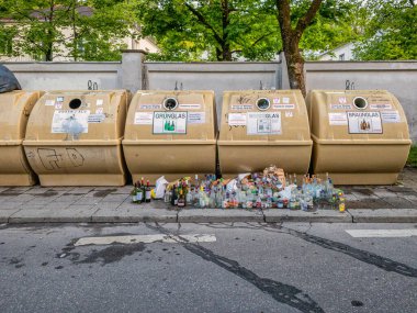 Dolu konteynırların önünde duran boş cam şişeler. Dünyadaki gerçek atık sorunlarının sembolü.